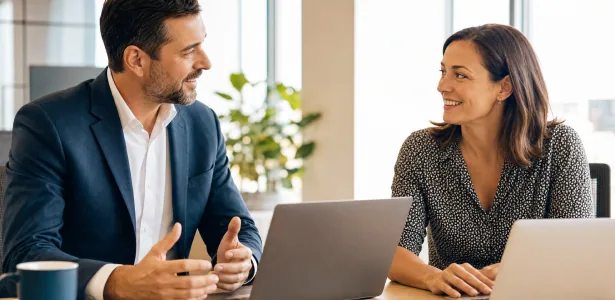 Two colleagues talking in Spanish across a desk at work